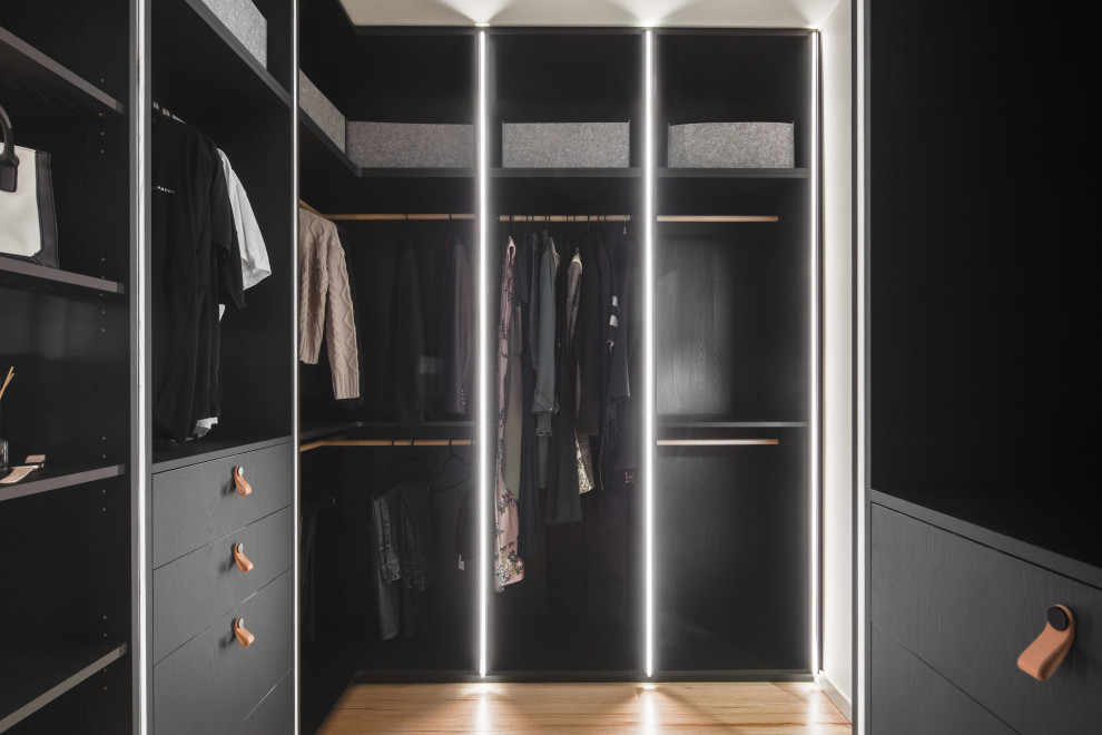 Immagine di una cabina armadio unisex minimal di medie dimensioni con ante a filo, ante nere, pavimento in legno massello medio e soffitto a cassettoni