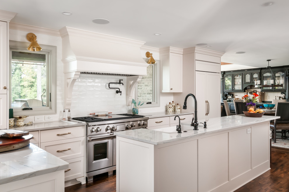 Design ideas for a mid-sized traditional kitchen in Atlanta with a farmhouse sink, shaker cabinets, white cabinets, quartzite benchtops, white splashback, mosaic tile splashback, stainless steel appliances, medium hardwood floors, with island, brown floor and white benchtop.