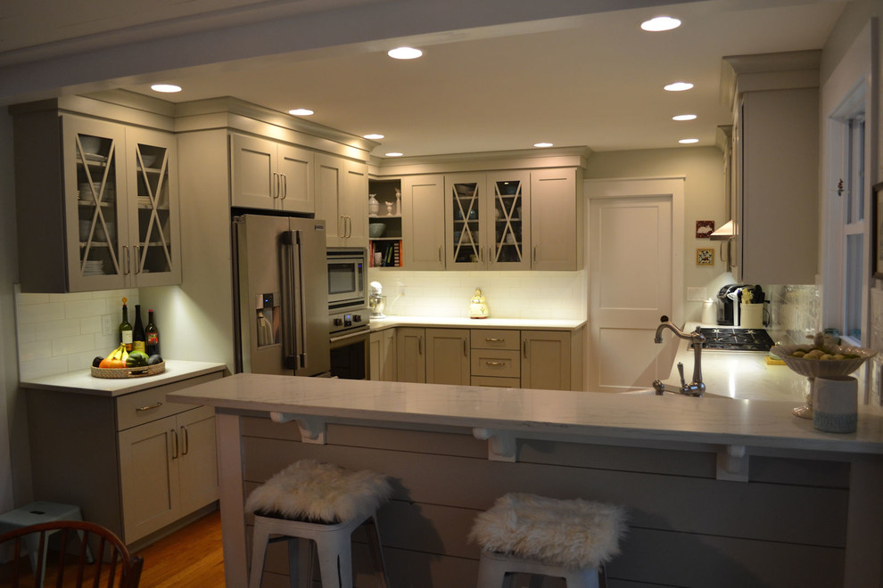 Inspiration for a mid-sized transitional u-shaped medium tone wood floor and brown floor eat-in kitchen remodel in Boston with a farmhouse sink, shaker cabinets, gray cabinets, granite countertops, white backsplash, ceramic backsplash, stainless steel appliances and white countertops