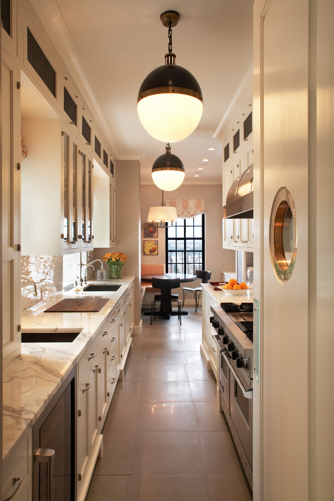 This is an example of a transitional galley separate kitchen in New York with glass-front cabinets, marble benchtops and stainless steel appliances.