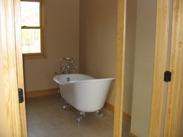 This is an example of a large country bathroom in Other with a claw-foot tub, a two-piece toilet, brown tile, ceramic tile, brown walls, ceramic floors and a pedestal sink.