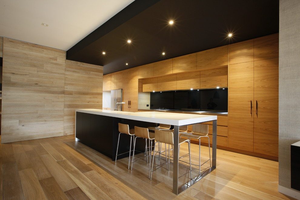 Photo of a mid-sized contemporary galley eat-in kitchen in Melbourne with flat-panel cabinets, medium wood cabinets, black splashback, glass sheet splashback, stainless steel appliances, quartz benchtops and medium hardwood floors.
