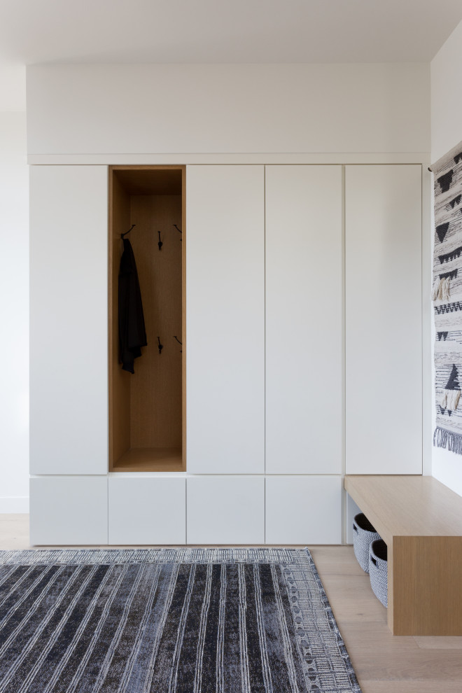 Réalisation d'un hall d'entrée design de taille moyenne avec un mur blanc, parquet clair, une porte pivot, une porte en bois foncé et un sol marron.