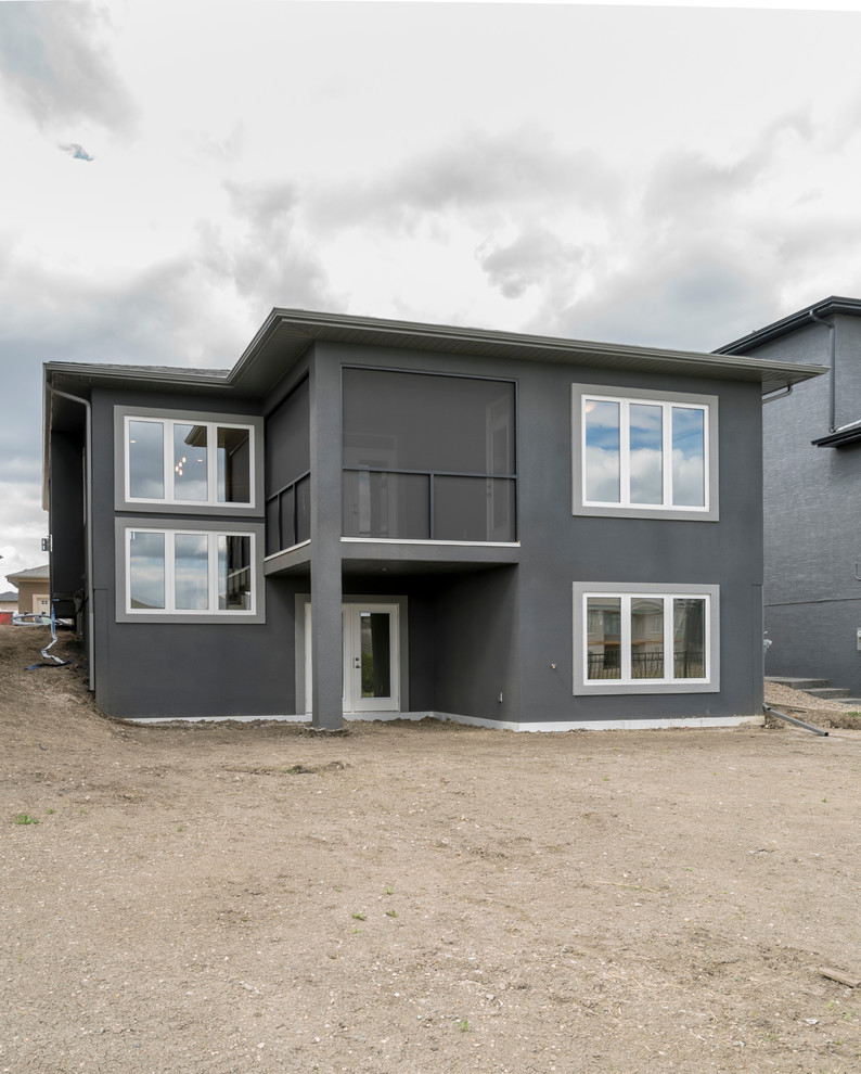 This is an example of a modern one-storey stucco grey house exterior in Other with a shingle roof.
