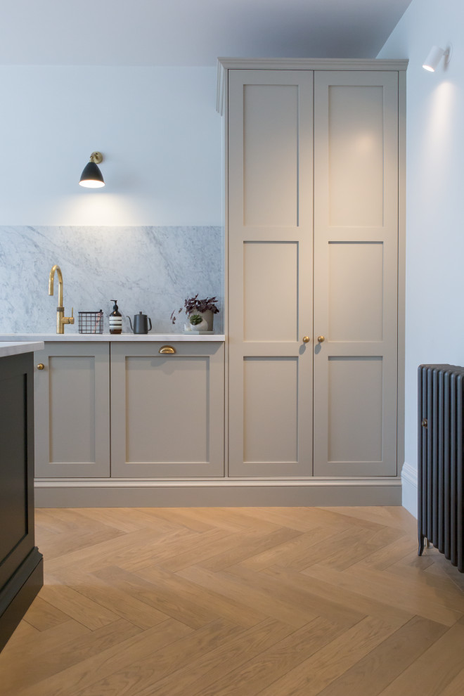 Inspiration for a large modern single-wall kitchen/diner in London with grey cabinets, an island and white worktops.