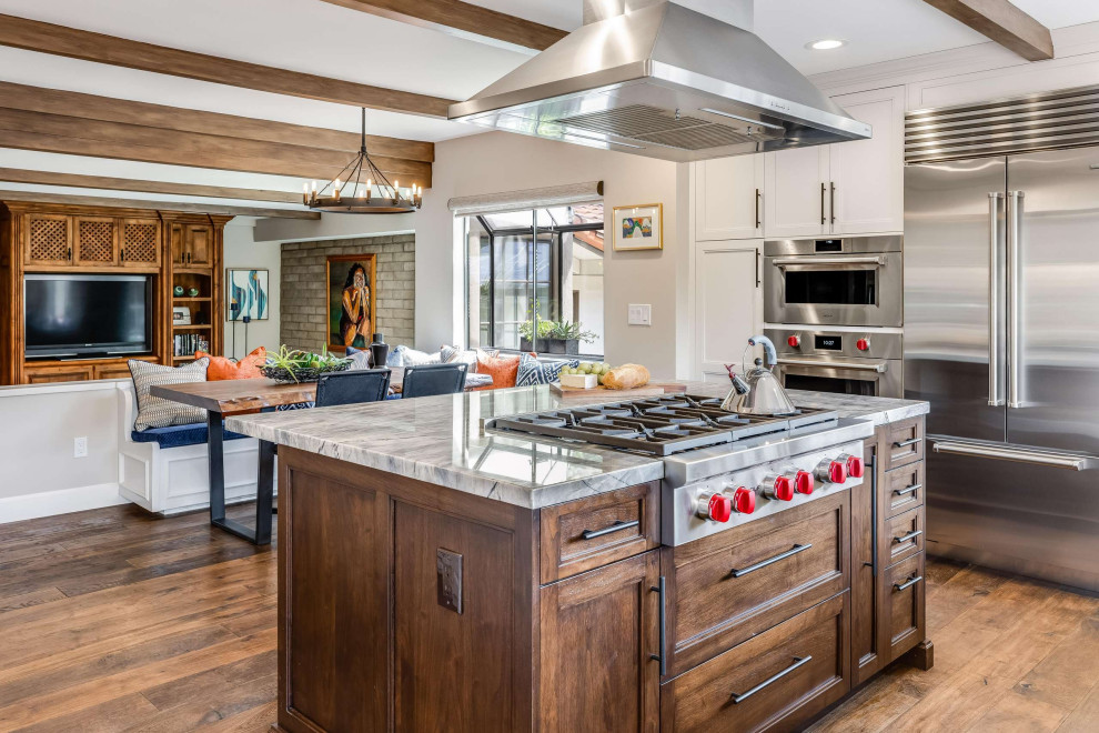 This is an example of a mediterranean eat-in kitchen in San Francisco with medium wood cabinets, stainless steel appliances, medium hardwood floors, with island, brown floor, grey benchtop, exposed beam, shaker cabinets and granite benchtops.