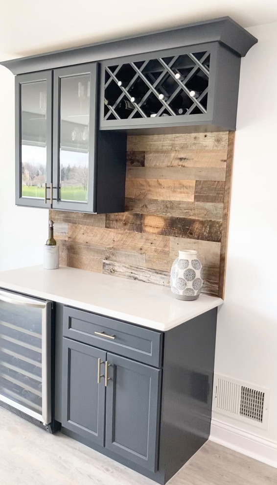 Photo of a mid-sized country single-wall home bar in Chicago with an undermount sink, shaker cabinets, grey cabinets, quartz benchtops, brown splashback, timber splashback, vinyl floors, brown floor and white benchtop.