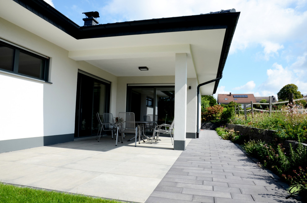 Large contemporary side full sun garden for summer in Frankfurt with natural stone paving and a raised bed.