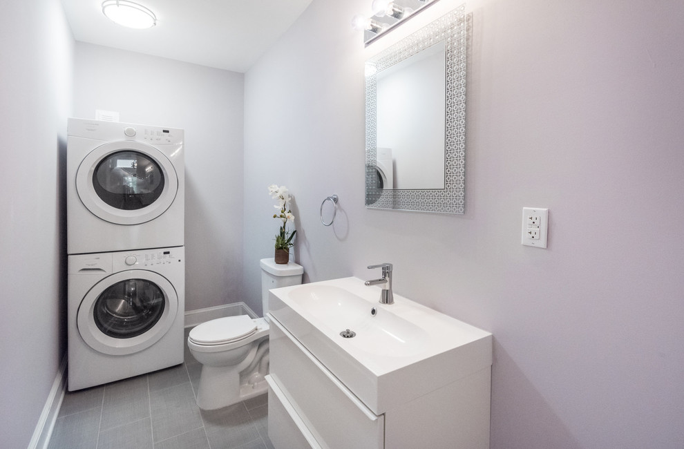 Mid-sized contemporary utility room in Wilmington with flat-panel cabinets, white cabinets, grey walls, vinyl floors, a stacked washer and dryer and a single-bowl sink.