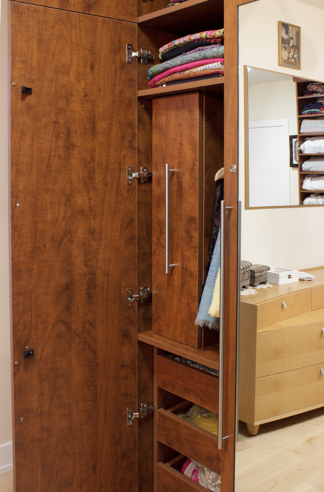 Photo of a mid-sized contemporary women's walk-in wardrobe in New York with flat-panel cabinets, medium wood cabinets and light hardwood floors.