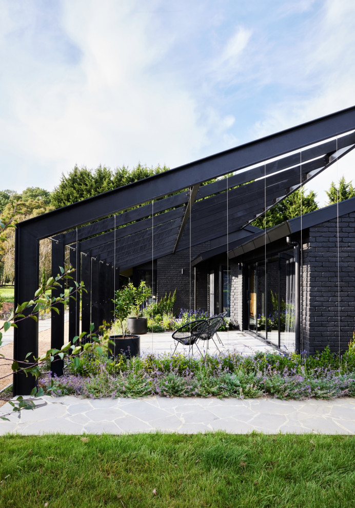 Inspiration for a large contemporary one-storey brick black house exterior with a hip roof and a metal roof.