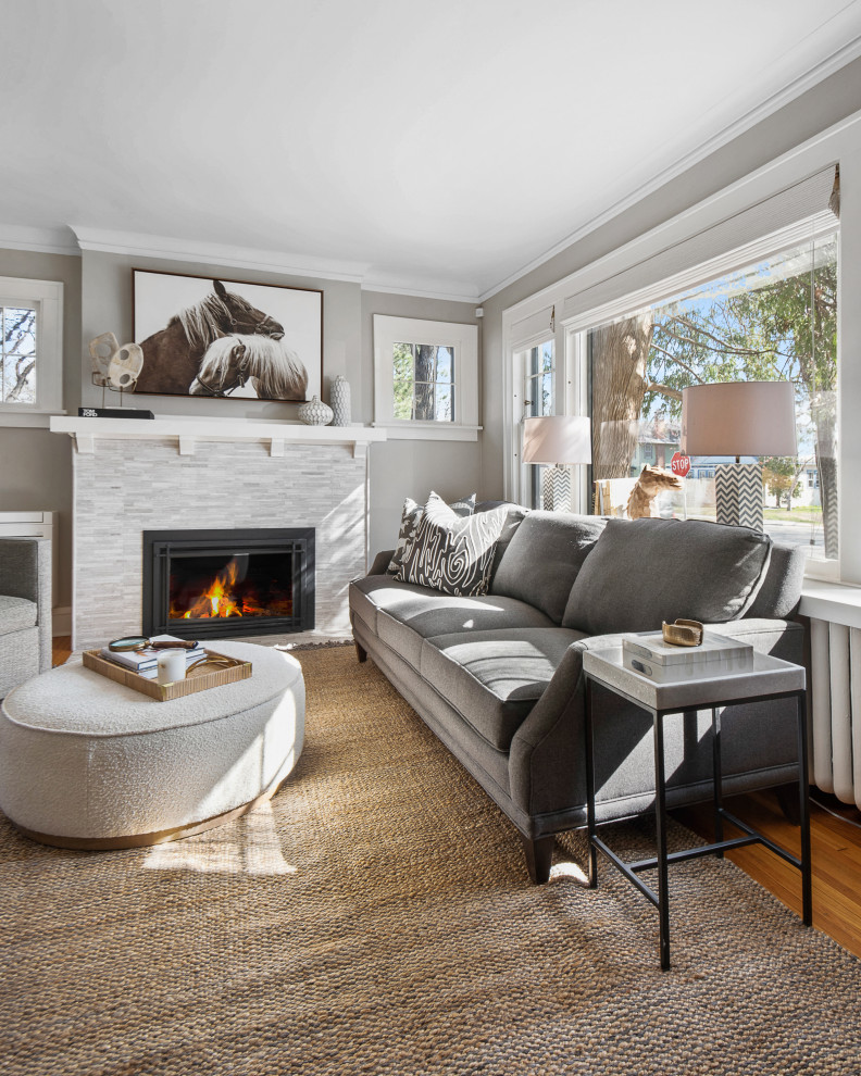 This is an example of a medium sized classic enclosed living room in Minneapolis with grey walls, medium hardwood flooring, a stacked stone fireplace surround, no tv and brown floors.