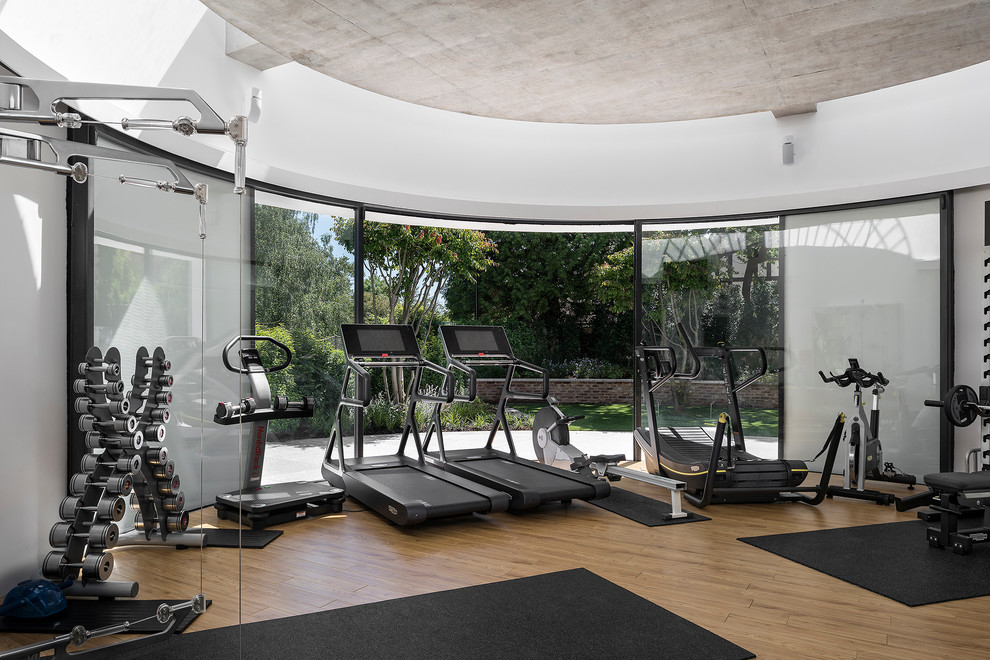 Large contemporary multipurpose gym in Hampshire with white walls and light hardwood floors.