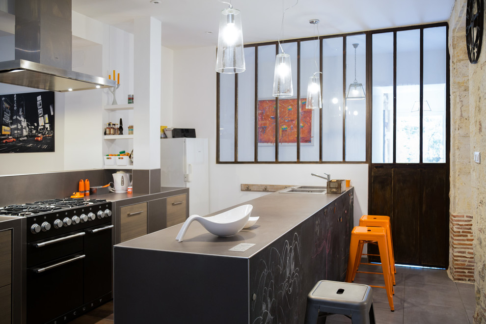 Photo of a mid-sized industrial open plan kitchen in Toulouse with medium wood cabinets, brown splashback, ceramic floors, a peninsula, a double-bowl sink and black appliances.
