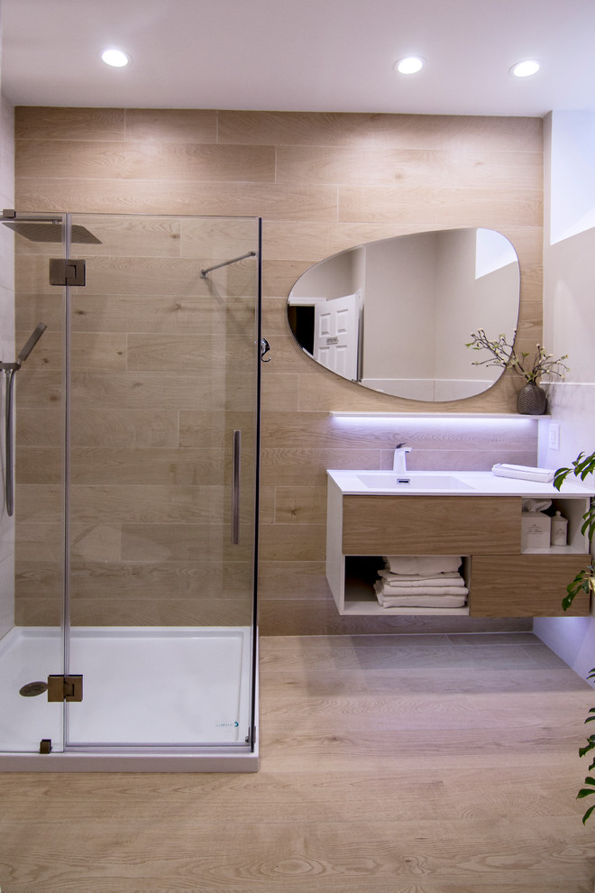 Photo of a mid-sized scandinavian 3/4 bathroom in New York with flat-panel cabinets, beige cabinets, a corner shower, a one-piece toilet, beige tile, porcelain tile, beige walls, porcelain floors, an integrated sink, solid surface benchtops, brown floor and a hinged shower door.