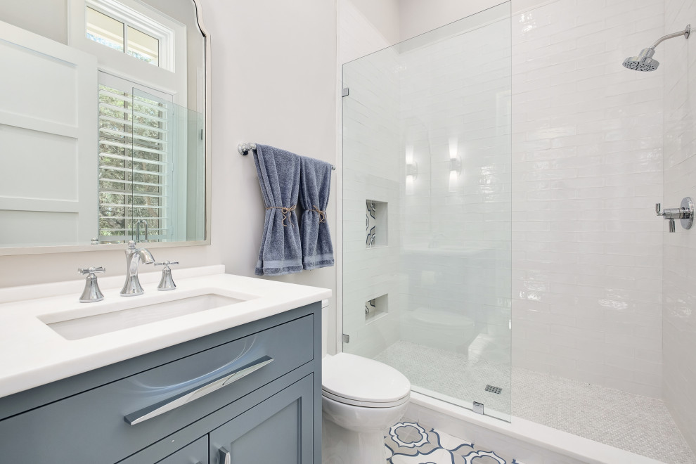Inspiration for a large beach style 3/4 wet room bathroom in Other with recessed-panel cabinets, blue cabinets, a one-piece toilet, white walls, ceramic floors, a drop-in sink, multi-coloured floor, a hinged shower door, white benchtops, a single vanity, a built-in vanity and vaulted.