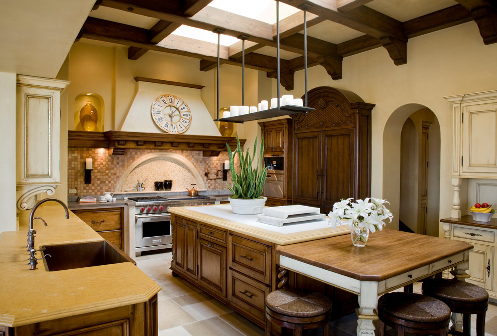 Inspiration for a mediterranean u-shaped separate kitchen in Los Angeles with a drop-in sink, raised-panel cabinets, marble benchtops, multi-coloured splashback, ceramic splashback, stainless steel appliances, limestone floors, with island, beige floor and beige benchtop.