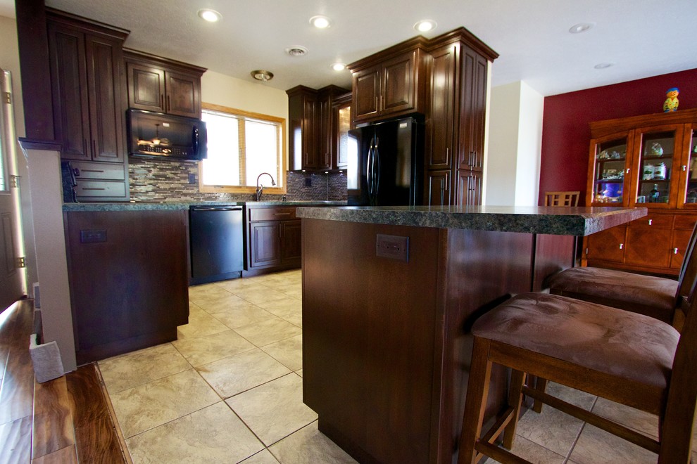 Kitchen - mid-sized u-shaped kitchen idea with an undermount sink, dark wood cabinets, laminate countertops, multicolored backsplash, glass tile backsplash, black appliances and an island