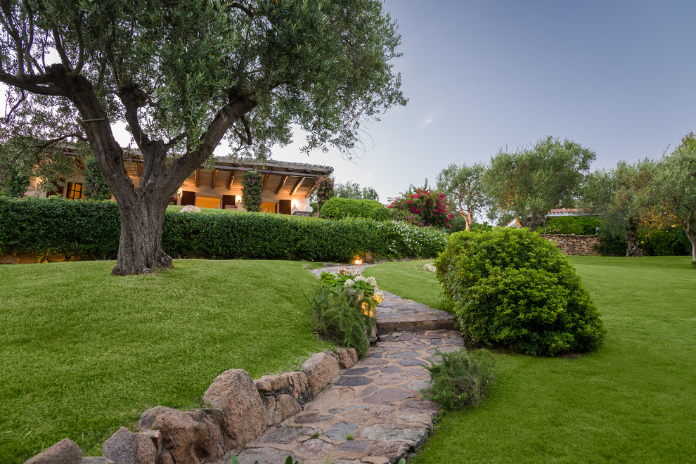 Expansive traditional sloped formal garden in Other with a garden path and natural stone pavers.