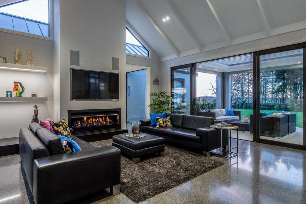 Photo of a large contemporary open concept living room in Auckland with grey walls, concrete floors, a standard fireplace, a built-in media wall and grey floor.