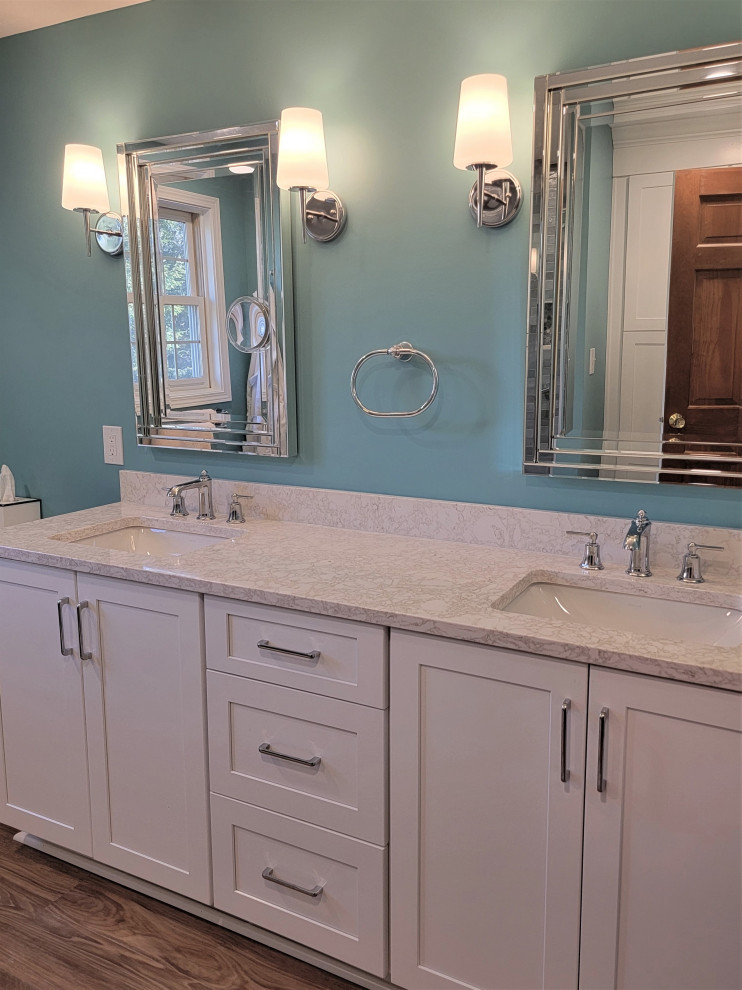 Photo of a mid-sized beach style master bathroom in Other with shaker cabinets, white cabinets, an open shower, a one-piece toilet, white tile, ceramic tile, blue walls, vinyl floors, an undermount sink, engineered quartz benchtops, brown floor, a hinged shower door, beige benchtops, a shower seat, a double vanity and a built-in vanity.