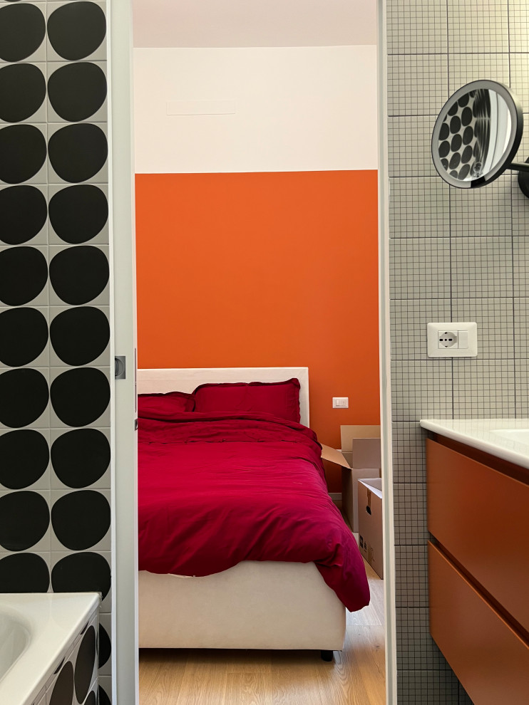 Стильный дизайн: главная ванная комната среднего размера в стиле модернизм с оранжевыми фасадами, раздельным унитазом, черно-белой плиткой, керамогранитной плиткой, белыми стенами, полом из керамогранита, монолитной раковиной, черным полом, белой столешницей, тумбой под одну раковину и подвесной тумбой - последний тренд