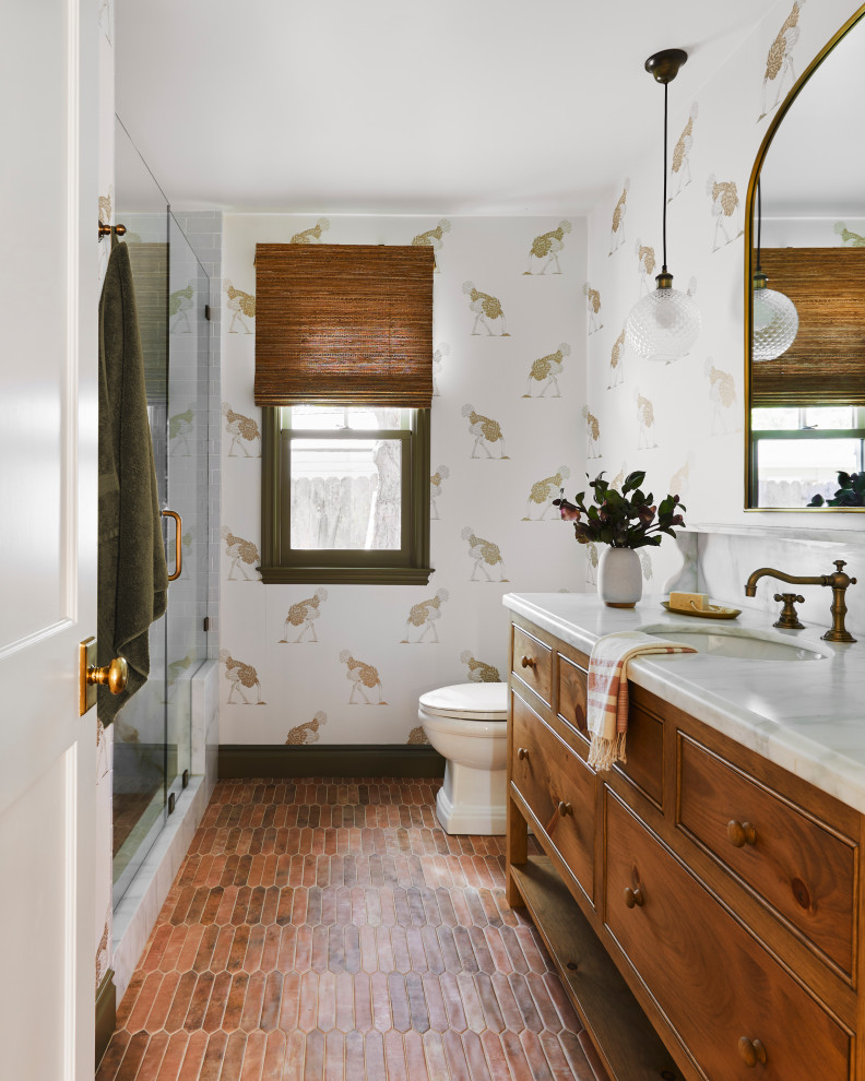 Photo of a traditional bathroom in San Francisco with flat-panel cabinets, medium wood cabinets, an alcove shower, multi-coloured walls, terra-cotta floors, an undermount sink, red floor, a hinged shower door, white benchtops, a single vanity, a freestanding vanity and wallpaper.