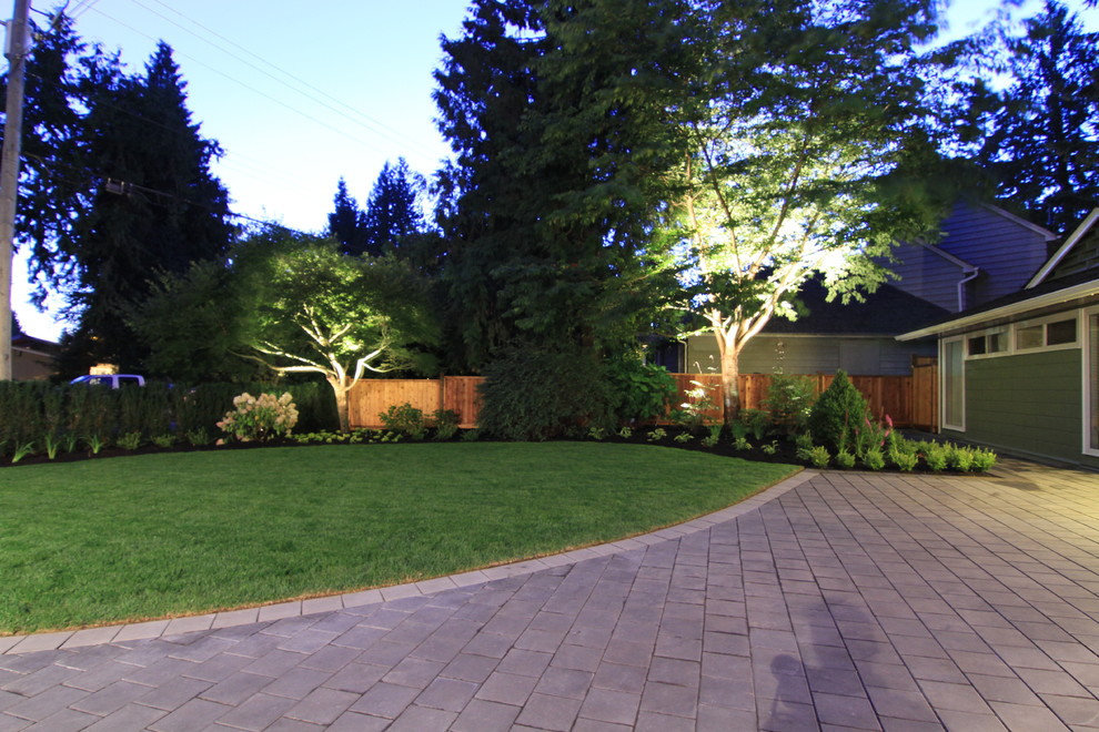This is an example of a mid-sized contemporary front yard full sun driveway in Vancouver with concrete pavers.