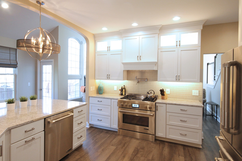 Design ideas for a large traditional eat-in kitchen in Grand Rapids with an undermount sink, shaker cabinets, white cabinets, quartz benchtops, yellow splashback, subway tile splashback, stainless steel appliances, medium hardwood floors, a peninsula and brown floor.