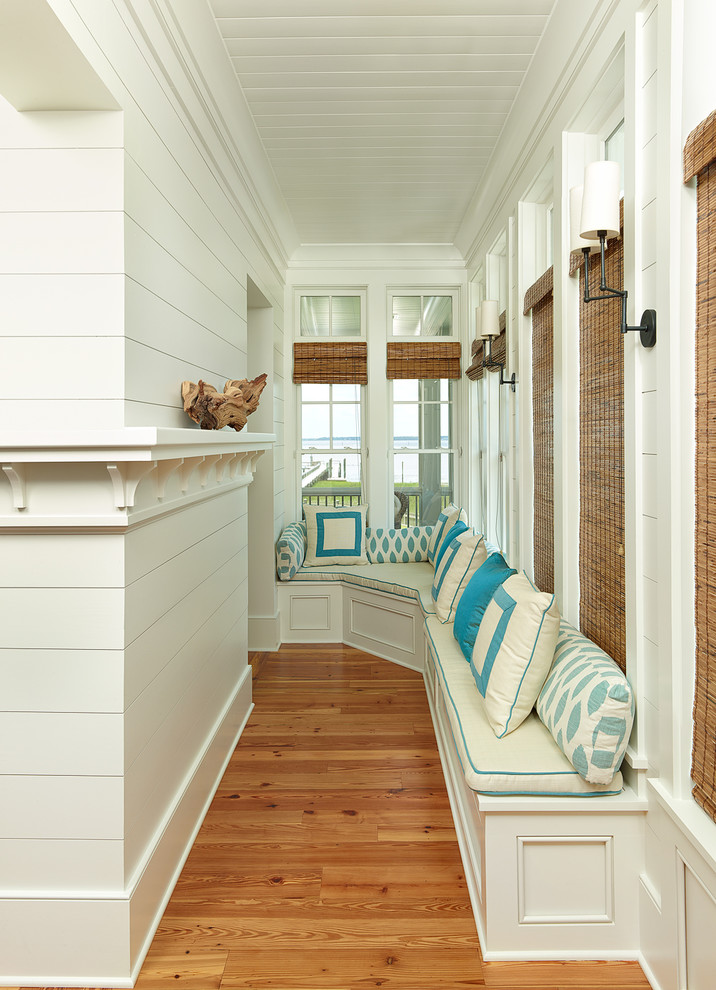 This is an example of a tropical entry hall in Charleston with white walls and medium hardwood floors.