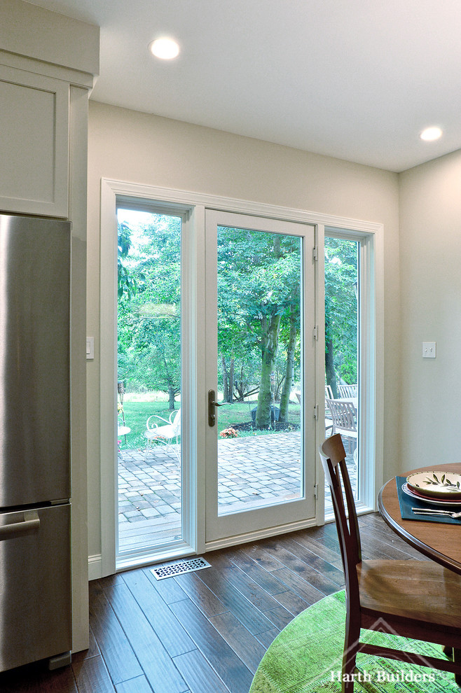 Mid-sized transitional l-shaped medium tone wood floor eat-in kitchen photo in Philadelphia with an undermount sink, recessed-panel cabinets, white cabinets, granite countertops, gray backsplash, glass tile backsplash, stainless steel appliances and an island