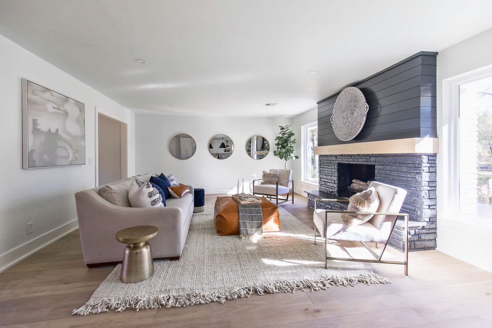 Photo of a mid-sized contemporary formal open concept living room in Oklahoma City with white walls, light hardwood floors, a standard fireplace, a brick fireplace surround, no tv and beige floor.