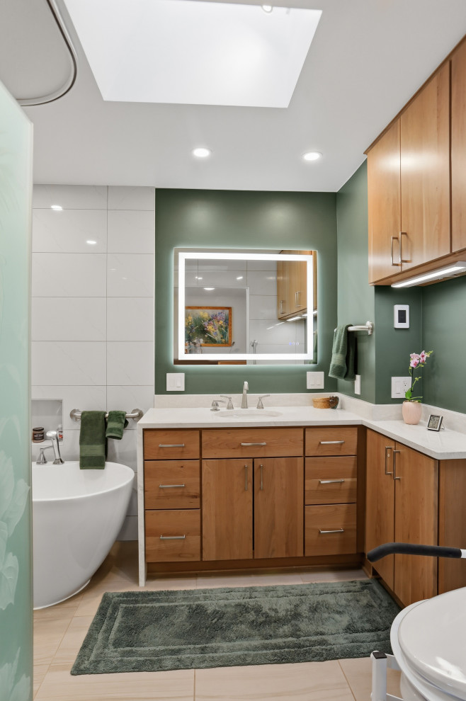 Example of a mid-sized transitional master white tile and porcelain tile single-sink, porcelain tile and beige floor freestanding bathtub design with flat-panel cabinets, medium tone wood cabinets, an undermount sink, white countertops, a freestanding vanity, a one-piece toilet and green walls