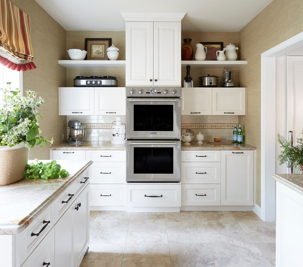 Inspiration for a mid-sized traditional u-shaped eat-in kitchen in Houston with a farmhouse sink, raised-panel cabinets, white cabinets, granite benchtops, white splashback, subway tile splashback, stainless steel appliances, travertine floors, with island and beige floor.