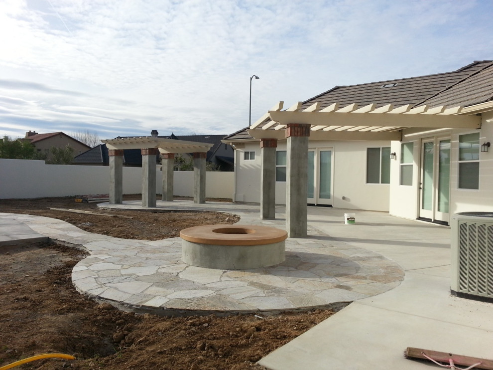 Foto di un grande patio o portico chic dietro casa con un focolare, lastre di cemento e una pergola