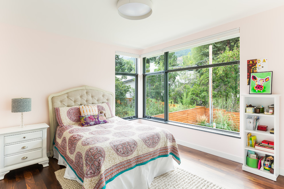 Idée de décoration pour une chambre d'amis vintage avec un mur rose et un sol en bois brun.
