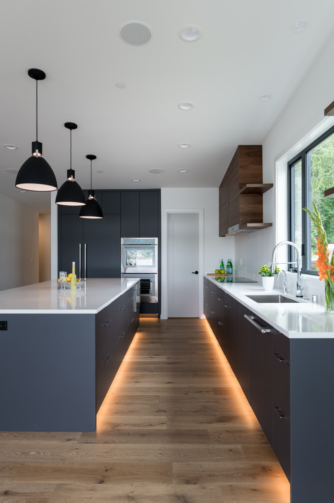 This is an example of a mid-sized modern l-shaped kitchen in Seattle with flat-panel cabinets, grey cabinets, quartzite benchtops, white splashback, panelled appliances, with island and white benchtop.