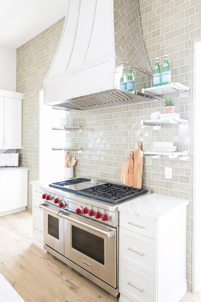 Example of a large transitional light wood floor and brown floor eat-in kitchen design in Phoenix with a farmhouse sink, white cabinets, marble countertops, green backsplash, ceramic backsplash, stainless steel appliances and two islands