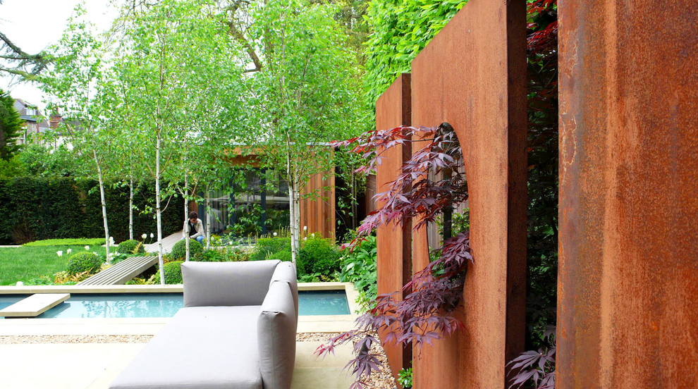Large contemporary backyard partial sun formal garden in London with a water feature and natural stone pavers.