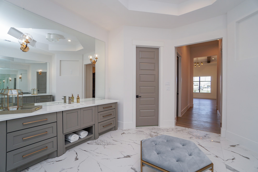 Large transitional master bathroom in Houston with shaker cabinets, grey cabinets, a freestanding tub, a shower/bathtub combo, a two-piece toilet, white tile, porcelain tile, white walls, porcelain floors, an undermount sink, glass benchtops, white floor, a hinged shower door and white benchtops.