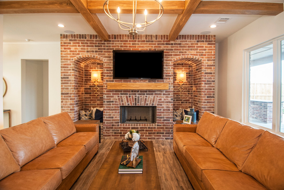 Photo of a mid-sized country open concept living room in Austin with white walls, medium hardwood floors, a standard fireplace, a brick fireplace surround, a wall-mounted tv and brown floor.