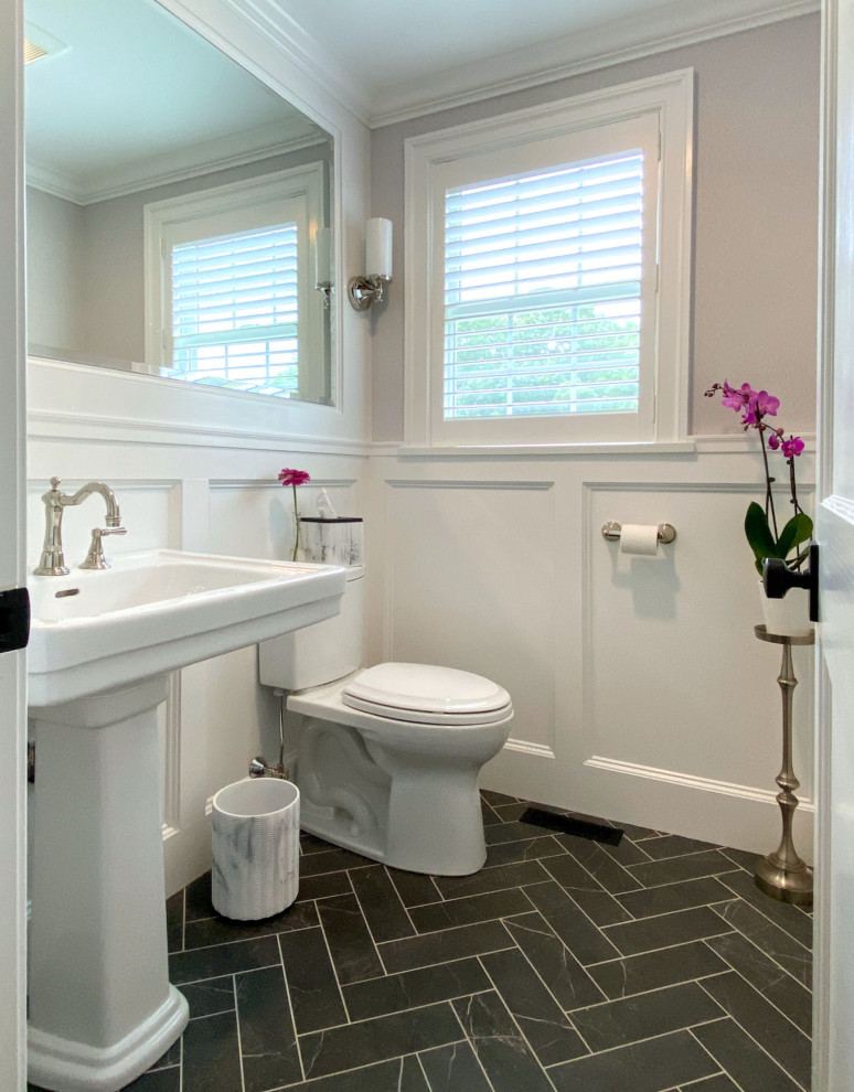 Example of a classic porcelain tile, black floor and wallpaper powder room design in Boston with a two-piece toilet and a pedestal sink