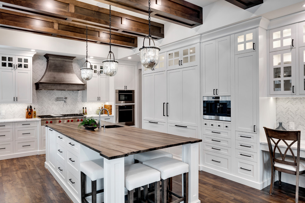 Inspiration for an expansive transitional u-shaped kitchen in Calgary with an undermount sink, shaker cabinets, white cabinets, marble benchtops, white splashback, marble splashback, stainless steel appliances, dark hardwood floors, with island, brown floor and white benchtop.