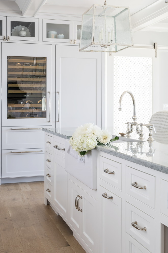 Example of a large transitional l-shaped light wood floor and beige floor open concept kitchen design in Boston with a farmhouse sink, shaker cabinets, gray cabinets, quartz countertops, white backsplash, subway tile backsplash, paneled appliances, an island and gray countertops
