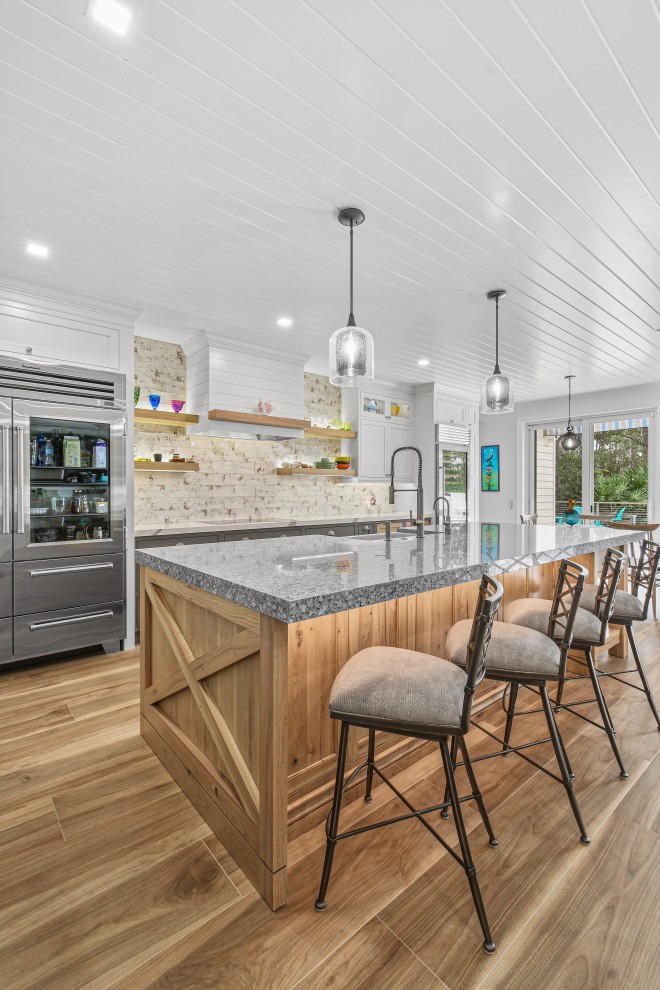 На фото: прямая кухня-гостиная в стиле лофт с фасадами в стиле шейкер, серыми фасадами, столешницей из переработанного стекла и островом с