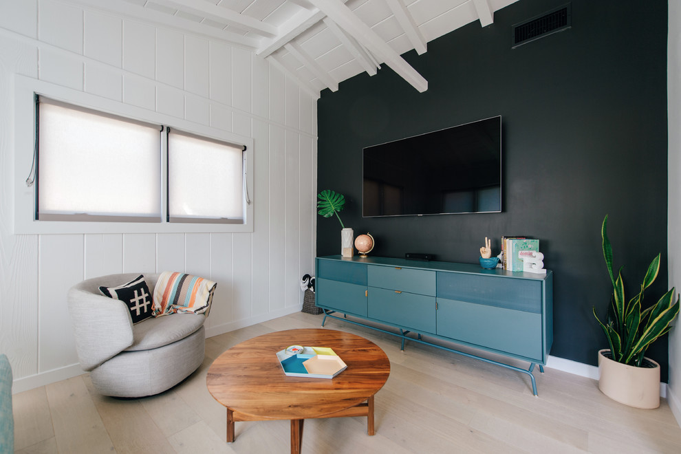 Photo of a small beach style enclosed family room in Orange County with a game room, black walls, light hardwood floors, a wall-mounted tv and beige floor.