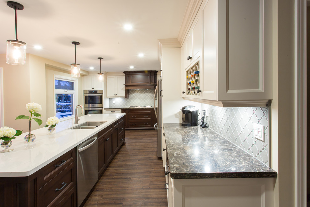 Inspiration for a large transitional l-shaped dark wood floor eat-in kitchen remodel in Orange County with a double-bowl sink, recessed-panel cabinets, white cabinets, granite countertops, gray backsplash, glass tile backsplash, stainless steel appliances and an island