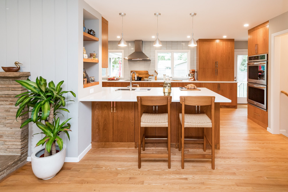 Inspiration for a large midcentury galley separate kitchen in Other with a single-bowl sink, flat-panel cabinets, medium wood cabinets, quartz benchtops, blue splashback, ceramic splashback, stainless steel appliances, medium hardwood floors, a peninsula, brown floor and white benchtop.