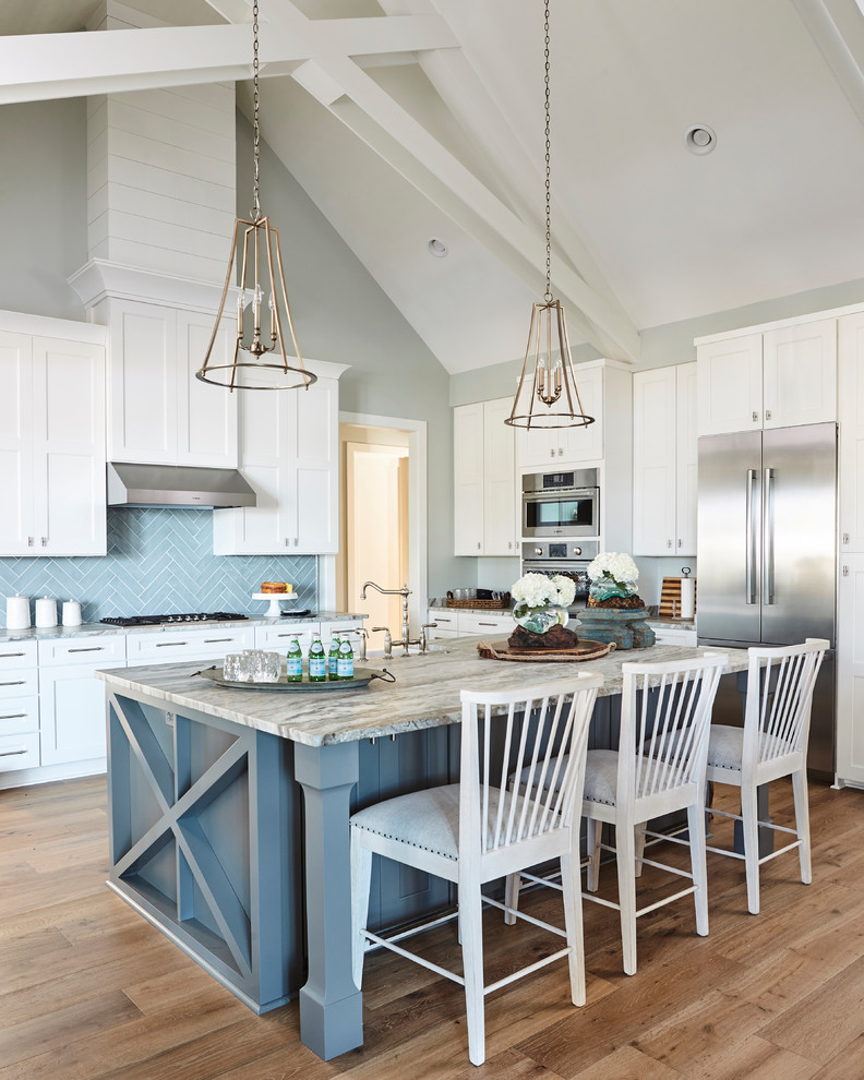 This is an example of a country u-shaped kitchen in Atlanta with shaker cabinets, blue splashback, stainless steel appliances, medium hardwood floors, with island, brown floor and white cabinets.