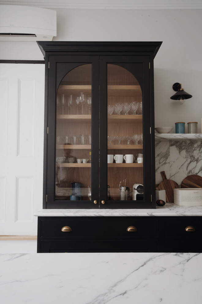 Inspiration for a medium sized classic galley kitchen/diner in London with a belfast sink, shaker cabinets, black cabinets, marble worktops, white splashback, marble splashback, black appliances, porcelain flooring, an island, blue floors, white worktops, a vaulted ceiling and feature lighting.
